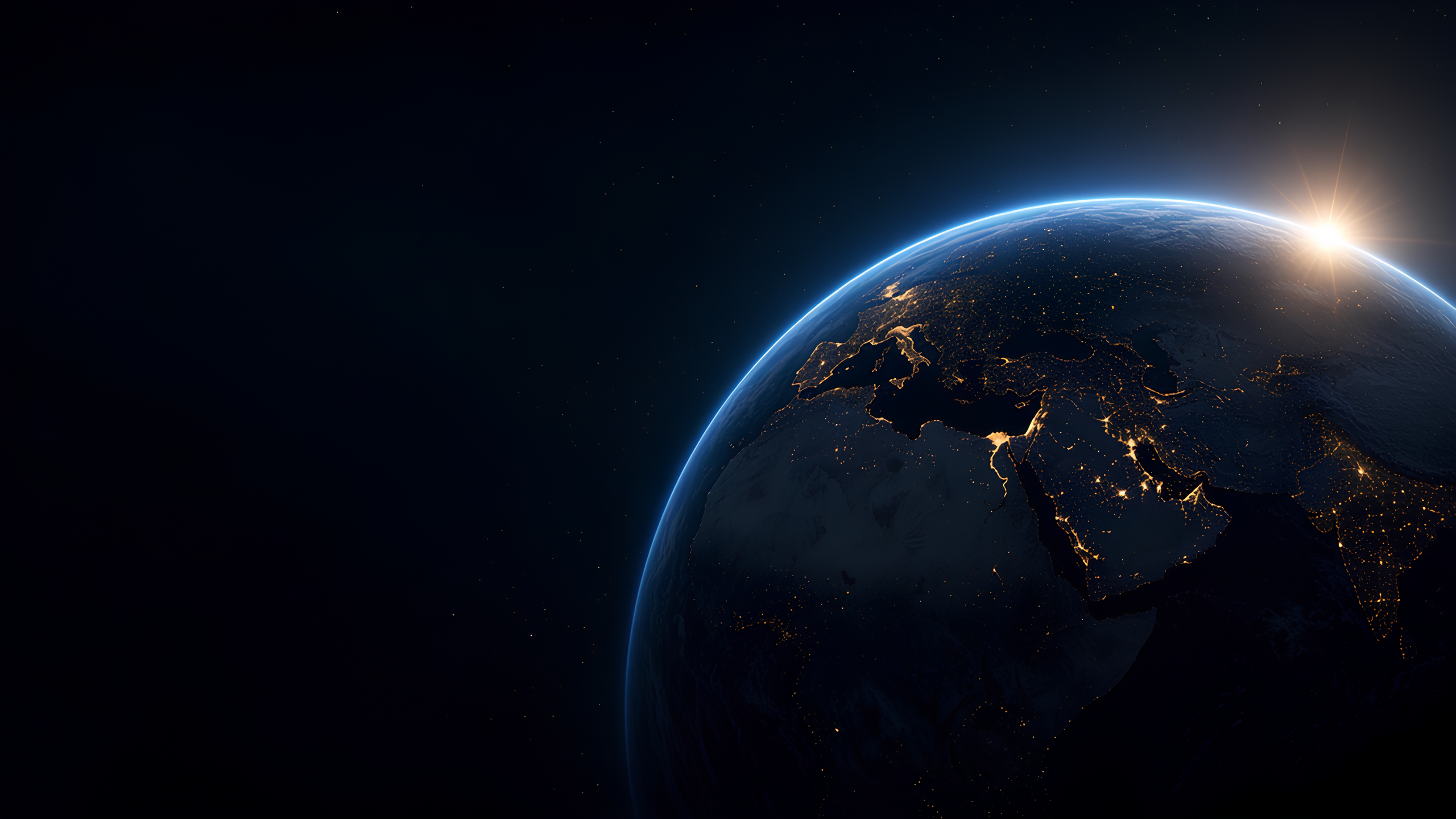 Earth from orbit at night, with city lights and sunrise along the horizon